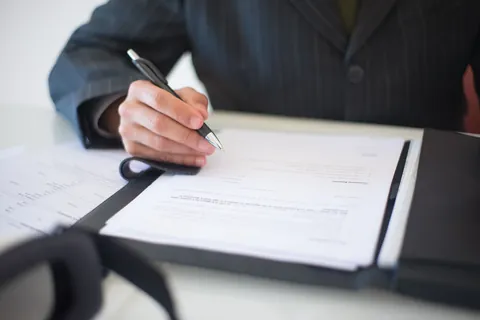 Dłoń podpisująca papierowy dokument